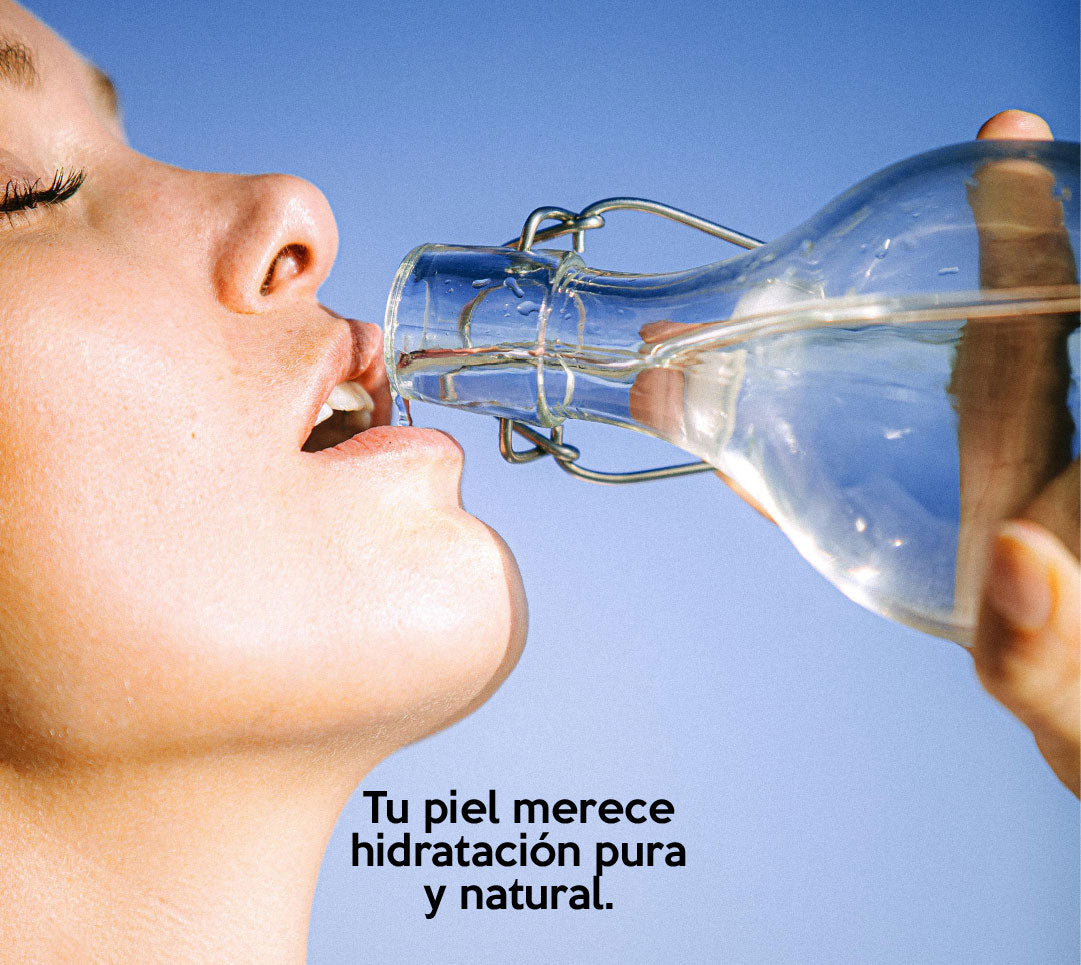 Mujer sosteniendo un vaso de agua, promoviendo la importancia de hidratar la piel desde adentro con ingredientes naturales para una belleza saludable