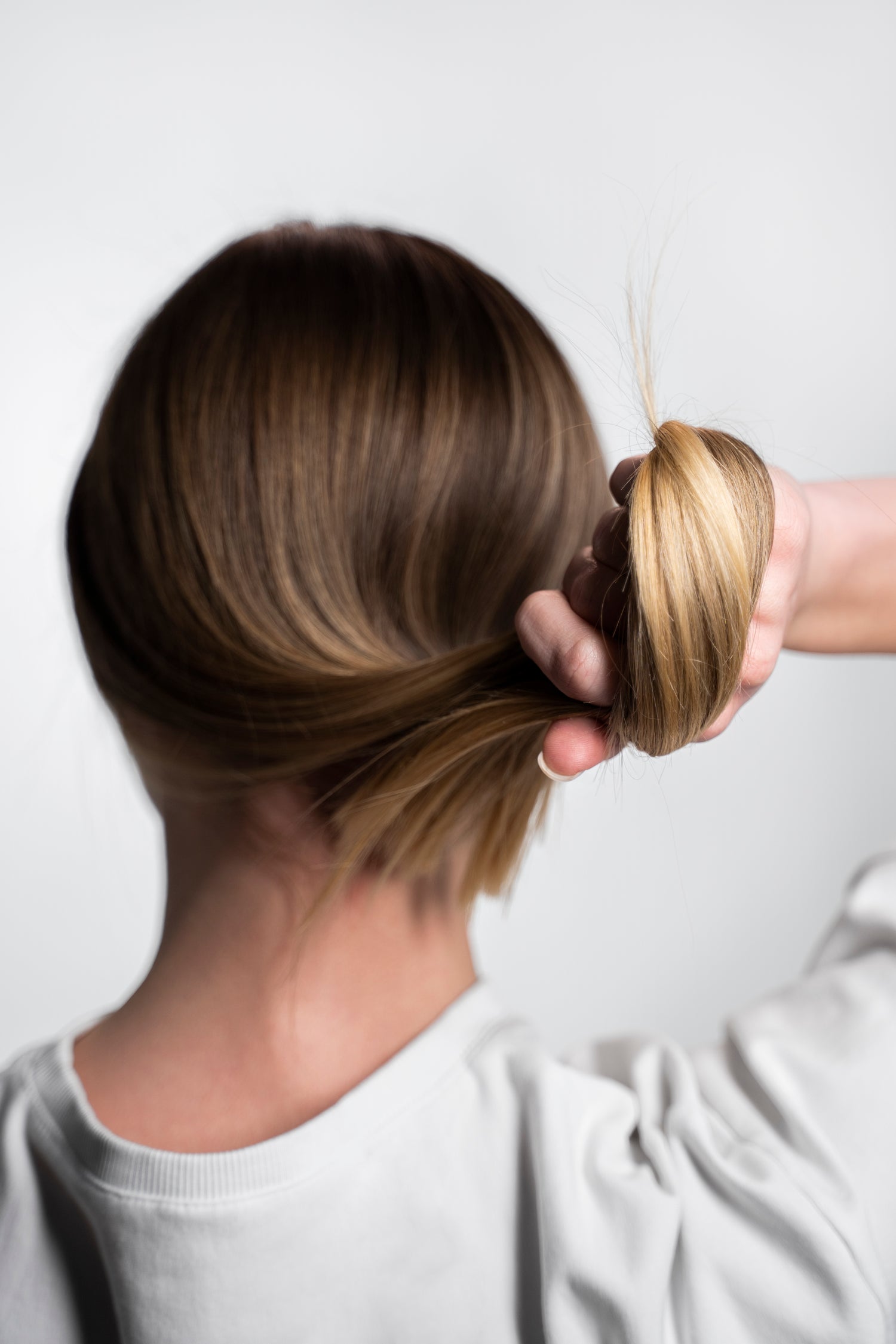 Mujer tirando de su cabello fuerte y brillante, demostrando la efectividad de productos naturales para fortalecer y revitalizar el cabello de forma saludable